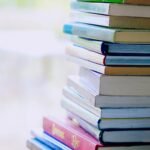 A tall stack of colorful hardcover books on a table indoors, perfect for library-themed concepts.